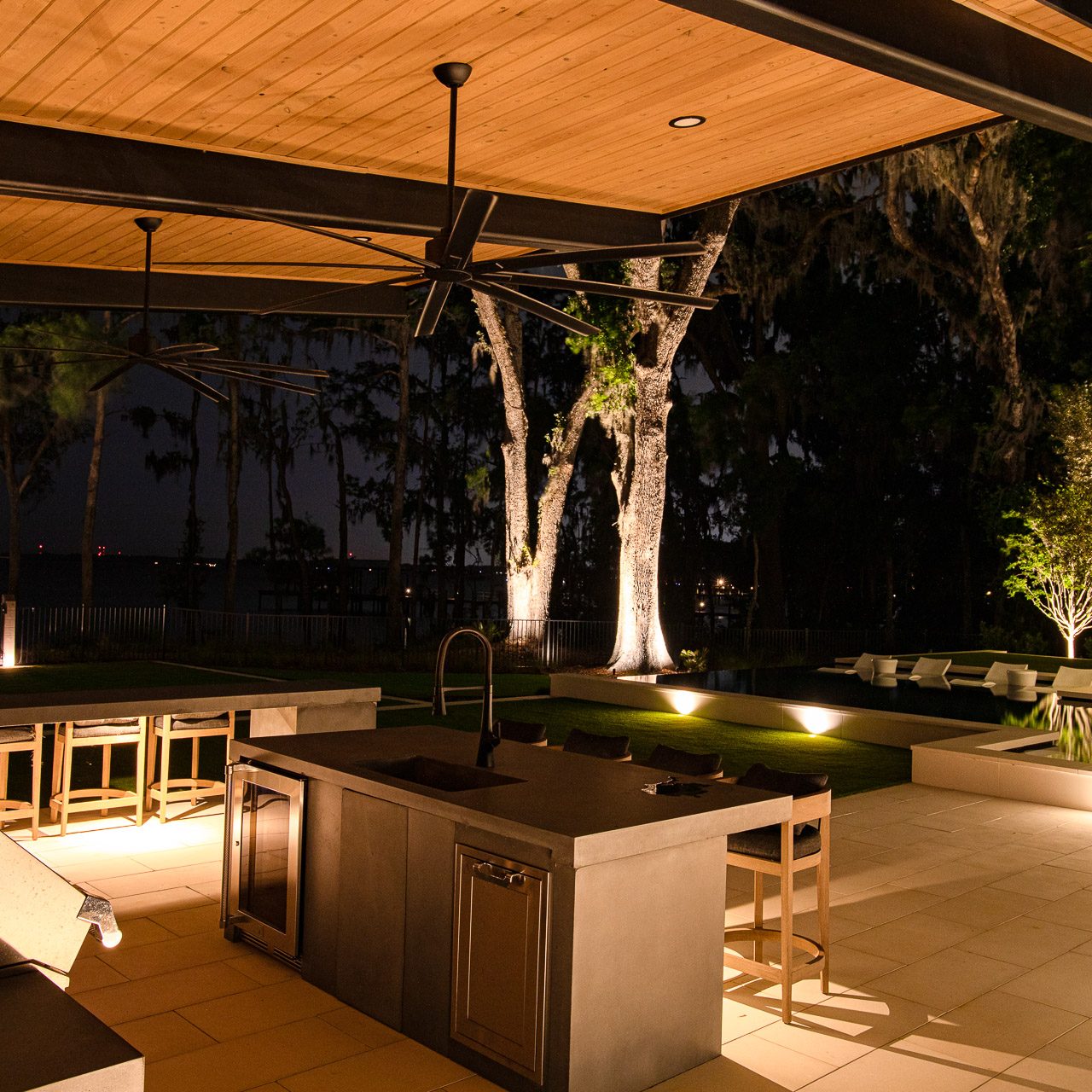 Elegant outdoor kitchen lit by Lucarelli outdoor lighting in river town neighborhood